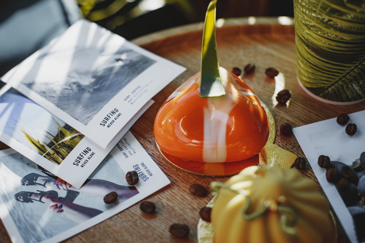Artistic shot of gourmet pastries with coffee beans and surf-themed flyers on a wooden table.
