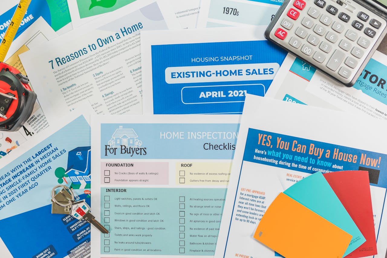 About Flat lay of real estate brochures, checklists, and a calculator for home buying.